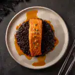 Salmão ao molho de maracujá sobre arroz negro, prato sofisticado e nutritivo.