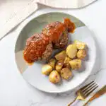Almôndegas com molho BBQ e batatas assadas em prato branco.