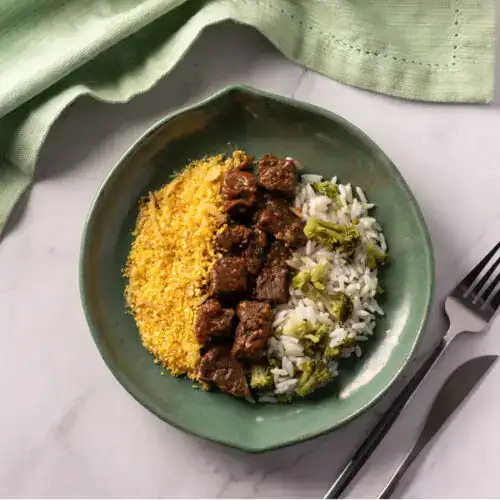 Prato com comida natural, arroz, carne e legumes, em prato verde.