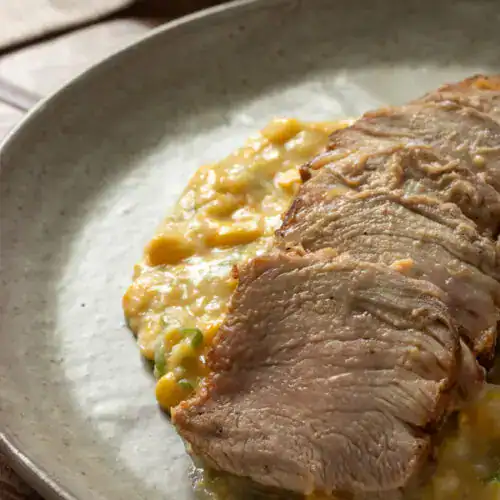 Carne suculenta com legumes e purê de batata em prato saudável.